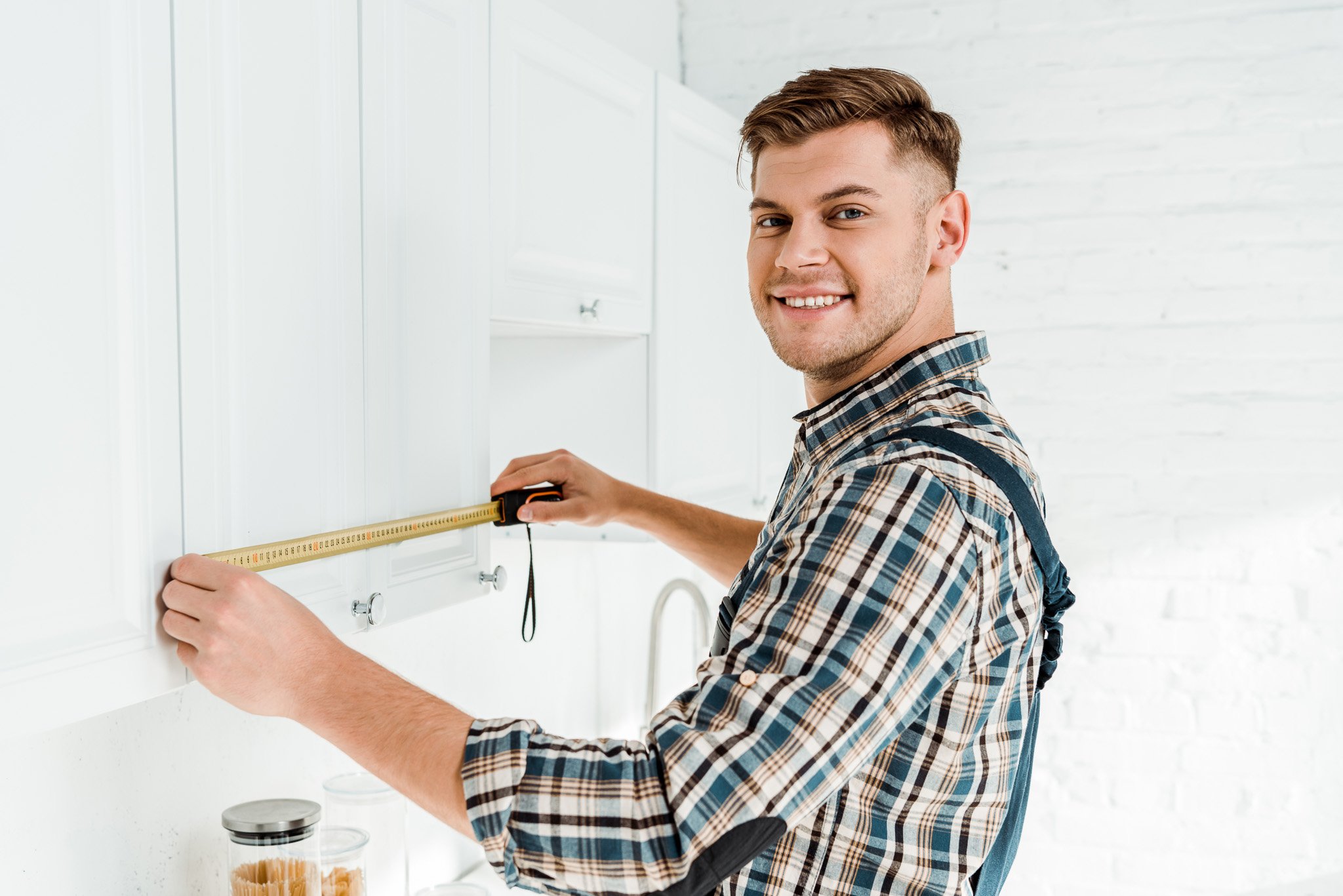 cheerful-installer-in-overalls-measuring-white-kit-2023-11-27-04-51-24-utc-1